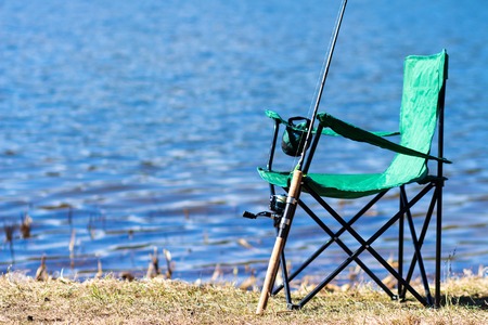 Fishing. Fishing rod and chair near lakeshore. Fisherman toolsの写真素材