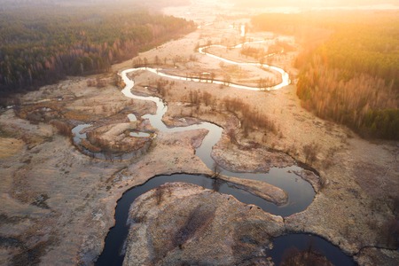 Bright sunrise over wild curved river aerial view. River landscape in sunlight from above