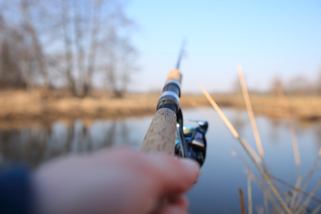 Fishing on spring river with spinning. Fisherman holding fishing rod in hands