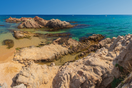 Rock on sandy sea resort beach in Costa Brava, Lloret de Mar. Summer amazing seascape on clear day in Spainの写真素材