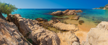 Panorama Lloret de mar sea beach on sunny clear day. Blue lagoon in Costa Brava with rocks on sand beach Cala Treumalの写真素材