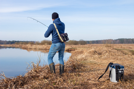 Fisherman catches fish in river at springtime. Man with spinning on fishingの写真素材