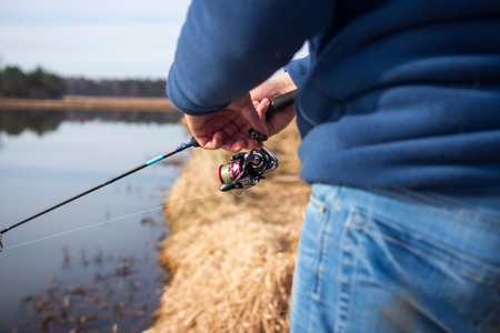 Fisherman catching fish by spinning. Fishing on riverの写真素材