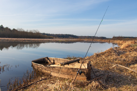 Rural landscape with boat and fishing rod on river side at spring. Fishing in springの写真素材