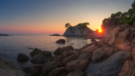 Sunrise on Costa Brava coast. Spanish sea landscape. Morning dawn on sea beach with rocks and cliffs.の写真素材
