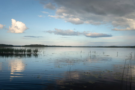 The vast sky with its drifting clouds is reflected flawlessly in the calm water, creating a dreamy...