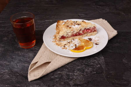 Shortcake and lemon in a white plate and tea in a glass cup on a towel on a dark backgroundの写真素材