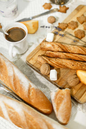 on the table is coffee in a cup, biscuits, buns, walnut, marshmallow, flower and wooden boardの写真素材