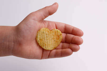 chips heart in hand on white backgroundの写真素材