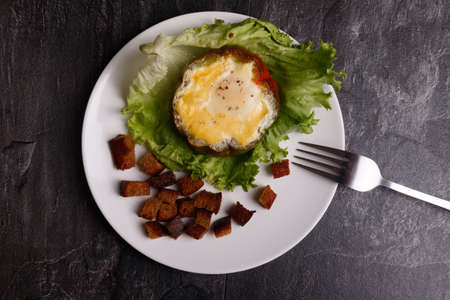 baked egg in pepper on a salad sheet with crackers in a white plateの写真素材