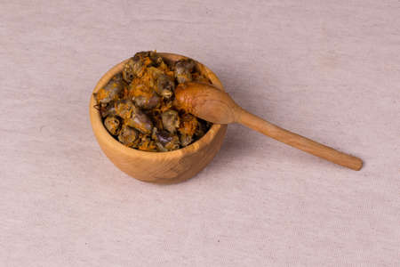 Braised chicken hearts in a wooden bowl, next to a wooden spoon on a wooden kitchen board.の写真素材