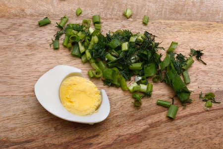 boiled egg and greens on a wooden boardの写真素材