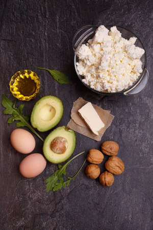A set of keto diet products. Meat, cottage cheese, walnuts, olive oil, chicken, avocados, greens and eggsの写真素材