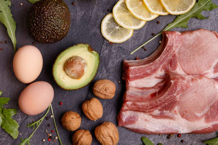 A set of keto diet products. Meat, walnuts, olive oil, chicken, avocado, lemon, greens and eggsの写真素材