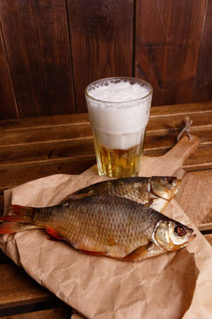 Close-up dried fish, a glass of beer on a dark wooden background.の写真素材