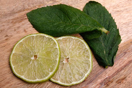 sliced lime and mint on a wooden boardの写真素材