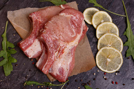 Chunks of meat on the bone in seasoning, next to it is greens and lemon. View from aboveの写真素材