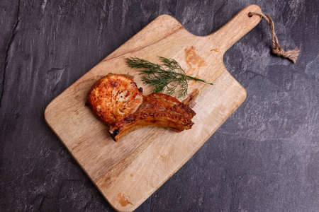 Meat - bone grill and dill on a kitchen wooden board. Top view, close-up