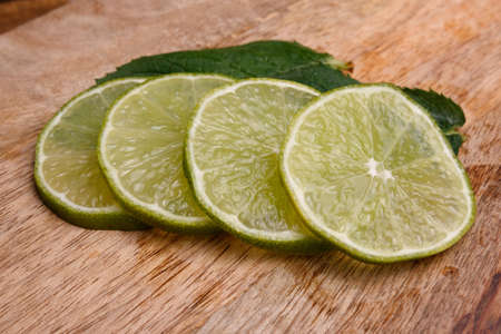 sliced lime and mint on a wooden boardの写真素材