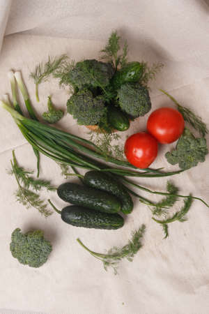 Green onions, cucumbers, tomatoes, broccoli and dill on a fabric backgroundの写真素材