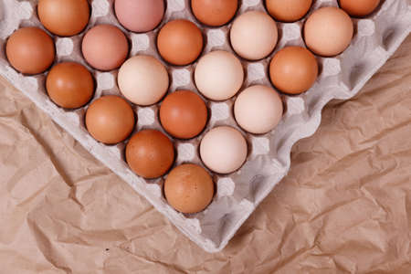 Yellow, beige and white chicken eggs in a paper container. Kraft paper background.