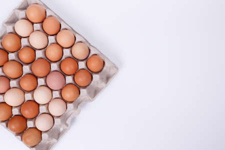 Yellow, beige and white chicken eggs in a paper container. Isolateのeditorial素材