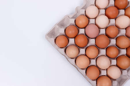 Yellow, beige and white chicken eggs in a paper container. Isolateのeditorial素材