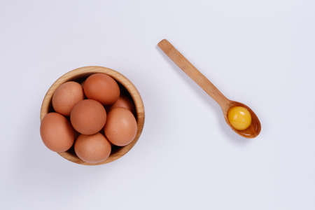 Yellow, beige and white chicken eggs in a wooden plate, one egg in a spoon. White background. Isolateのeditorial素材