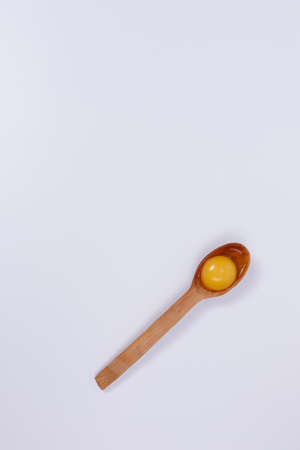 Egg yolk in a wooden spoon. White background. Isolateのeditorial素材