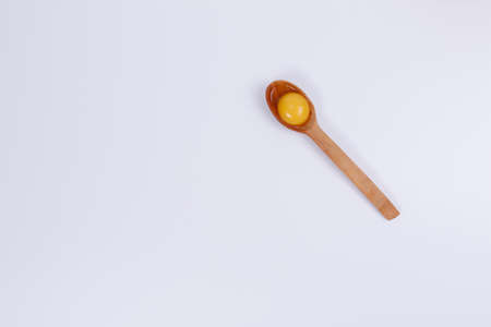 Egg yolk in a wooden spoon. White background. Isolateのeditorial素材