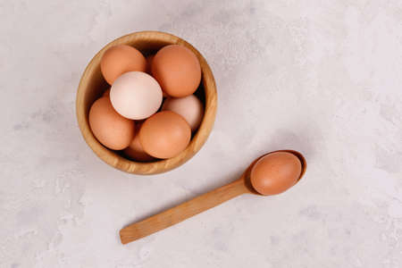 Rustic eggs in a wooden plate, one egg in a spoon. Close-up. View from above