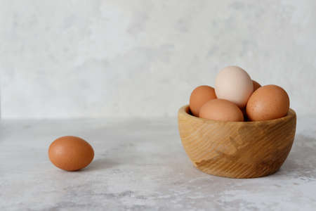 Chicken eggs in a wooden plate, one egg lies on the side. Close-up. Side viewの写真素材