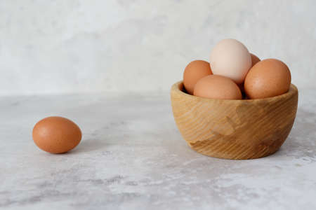 Chicken eggs in a wooden plate, one egg lies on the side. Close-up. Side viewの写真素材