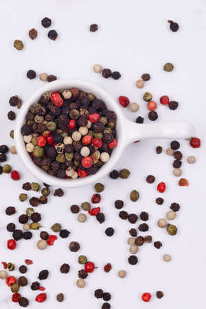 A mixture of multi-colored pepper in a small saucer on a white background. Isolateの写真素材