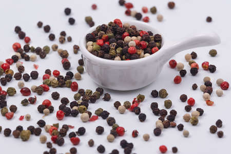 A mixture of multi-colored pepper in a small saucer on a white background. Isolate Macro shot. Close-upの写真素材