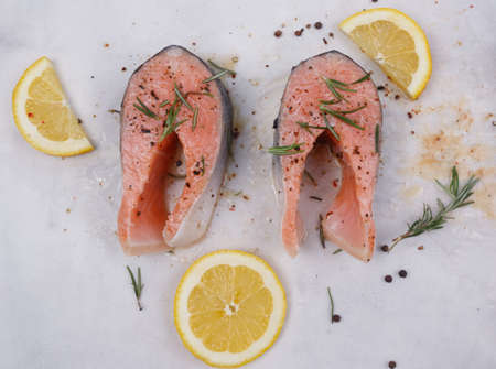 Raw salmon steaks, rosemary, lemon and seasoning. Close-up. View from above.の写真素材