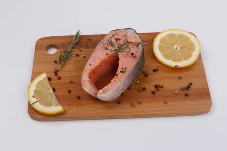 Raw salmon steaks, rosemary, lemon and seasoning on the kitchen board. Close-up. View from above. Isolateの写真素材