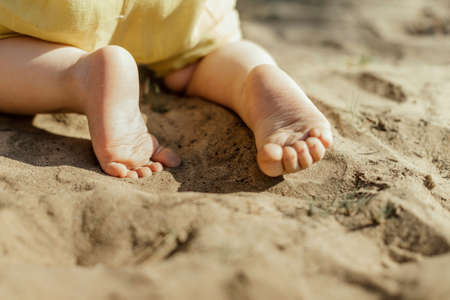 Feet of a child crawling on the sand. Close-upの写真素材