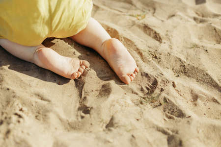 Feet of a child crawling on the sand. Close-upの写真素材