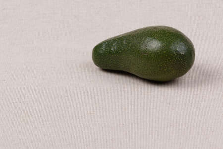 Whole avocado on a fabric background. Close-up