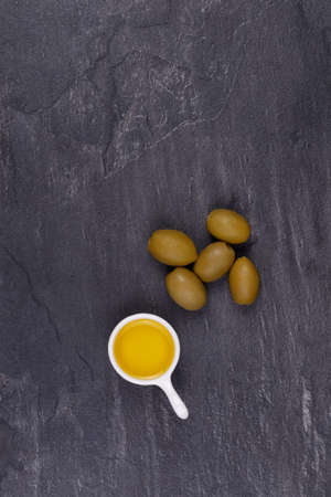 Olives and olive oil in a bowl on a black background. View from aboveの写真素材