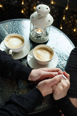 Hands of a man and woman close-up in sharpness, outside the sharpness of coffee in a cupの写真素材