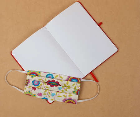 Notepad with blank white sheets and antivirus mask. Close-up. View from above.