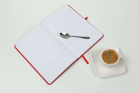 Cup of coffee, notebook and spoon on a white background. Close-up. View from above.の写真素材