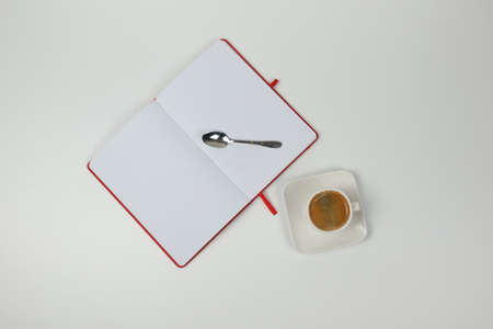 Cup of coffee, notebook and spoon on a white background. Close-up. View from above.の写真素材