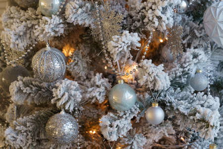 The Christmas tree is covered with hoarfrost and decorated with balls, beads, a garland and snowflakes.の写真素材