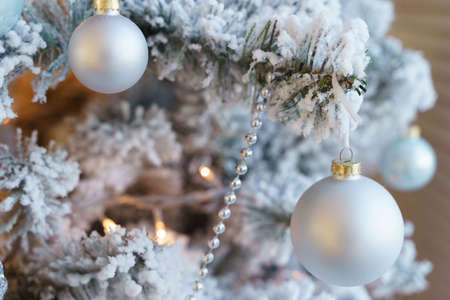 The Christmas tree is covered with hoarfrost and decorated with balls, beads and a garland.の写真素材