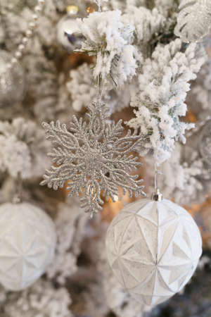 The Christmas tree is covered with hoarfrost and decorated with balls, beads, a garland and snowflakes.の写真素材