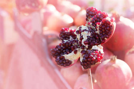 In the foreground is a cut pomegranate. Pomegranates in the background in pinkの写真素材