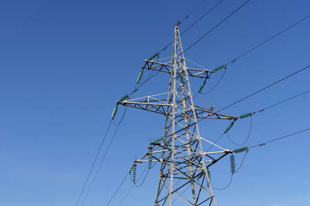 High voltage tower and power lines against a blue sky